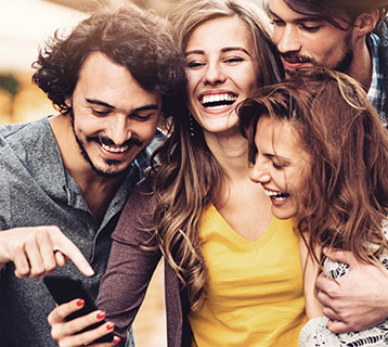 a happy group of friends looking at their friends phone